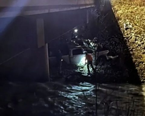 a truck stuck in a river under a bridge